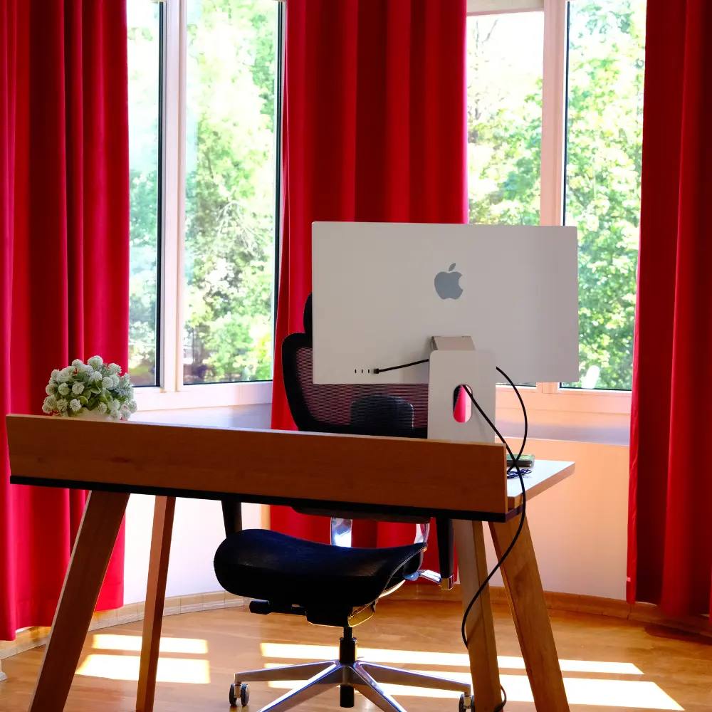 Stanowisko pracy z iMakiem na tle czerwonych zasłon w biurze BH Marketing